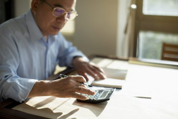 Senior man calculating finances Taiwanese senior man sitting at table and calculating finances